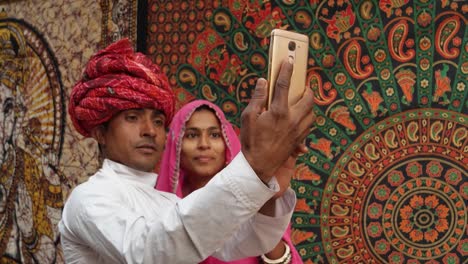 Vestidos-de-tiro-mano-de-pareja-tradicional-de-la-India-tomando-un-selfie-en-una-cámara-de-teléfono-móvil-en-Pushkar,-Rajastán