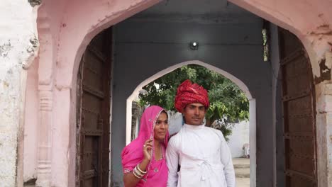 Amantes-de-la-pareja-India-de-pie-en-frente-del-viejo-arco-de-entrada-arquitectónica-patrimonio-en-Rajasthan,-India