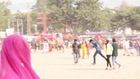 Pan-left-to-Rajasthani-smart-and-beautiful-couple-at-the-busy-fairgrounds-of-Pushkar-Fair,-India