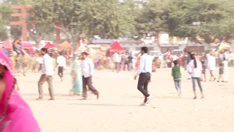 Pan-to-beautiful-Indian-couple-in-traditional-clothing-at-the-busy-fairgrounds-of-Pushkar-Fair,-India