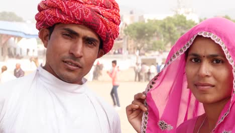 Tilt-up-to-attractive-Indian-couple-looking-straight-to-the-camera-at-the-fairgrounds-of-Pushkar-Fair,-Rajasthan,--India