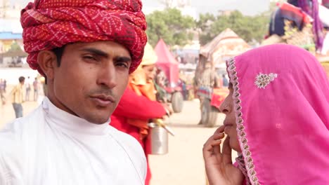 Tilt-up-to-portrait-of-beautiful-Indian-couple-in-traditional-clothing-at-the-busy-fairgrounds-of-Pushkar-Fair,-India