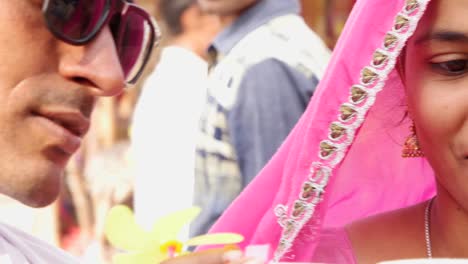 Wife-in-pink-sari-blows-bubbles-while-her-husband-in-black-sunglasses-and-red-turban-watches