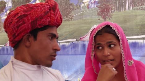 Paar-sprechen-sitzen-vor-einem-gemalten-Zelt-auf-der-Pushkar-Mela-Festival-Camel-Fair,-Rajasthan,-Indien