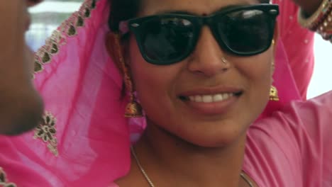 Beautiful-Indian-woman-wearing-sunglasses-and-pink-sari-with-her-man-in-red-turban-in-Pushkar,-Rajasthan,-India