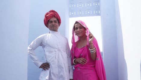 Cambio-de-enfoque-a-una-hermosa-novia-tradicional-y-el-novio-en-ropa-tradicional-contra-un-fondo-azul-en-la-India