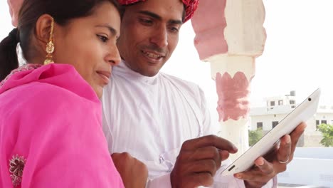 Traditional-Indian-wife-and-husband-working-learning-teaching-on-a-tablet-in-Rajasthan,-India