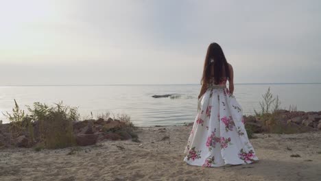 Pretty-girl-in-a-long-beautiful-dress-walks-by-the-river