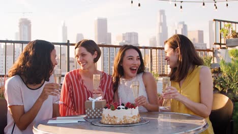 Porträt-von-Freundinnen-Geburtstag-auf-Dachterrasse-mit-Skyline-der-Stadt-im-Hintergrund