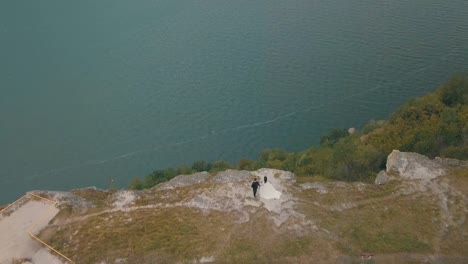 Junge-und-schöne-Hochzeitspaar-zusammen-am-Hang-des-Berges-in-der-Nähe-von-Meer.-Schönen-Bräutigam-und-Braut.-Aufnahmen-aus-der-Luft.-Luftaufnahme