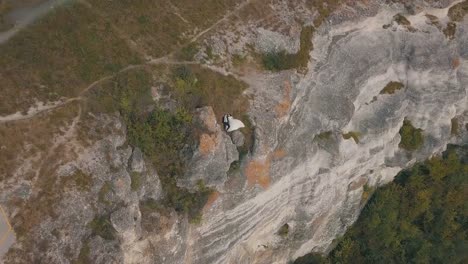 Joven-y-hermosa-pareja-junto-en-la-ladera-de-la-montaña-cerca-del-mar.-Hermoso-novio-y-novia.-Disparos-desde-el-aire.-Toma-aérea