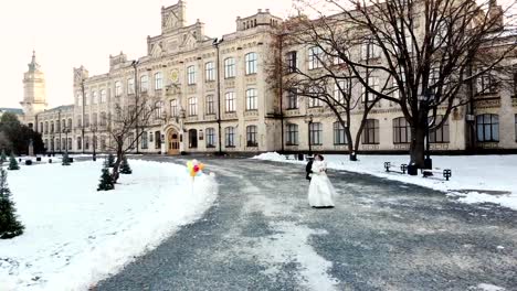 Winter-Hochzeit.-Luftaufnahme-des-Brautpaar-in-Brautkleider-sind-Tanz-Hochzeit-in-einem-verschneiten-Park,-vor-dem-Hintergrund-der-antiken-Architektur-und-Pflastersteine