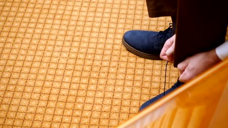 primer-plano,-las-manos-de-los-hombres-atan-cordones-de-los-zapatos.-hombre-se-pone-sus-zapatos-de-gamuza-azul-elegante,-en-el-fondo-de-la-alfombra.-Preparación-para-la-boda-del-novio