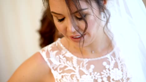 Close-up,-Braut-Gebühren.-die-Braut-ist-für-die-Hochzeit-gekleidet.-Porträt-einer-lächelnden,-schönen-Braut-in-Schleier-und-Spitze-Kleid.-Brautjungfer-Schnürsenkel-bis-weißer-Spitze-Kleid-mit-Schleife.-Details-der-Hochzeit-Kleid