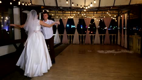 Winterabend,-eine-Terrasse-mit-Glühbirnen,-dekoriert-in-der-Straße-tanzen-das-Brautpaar-ihre-erste-Hochzeit-tanzen,-einen-Walzer.-Winter-Hochzeit