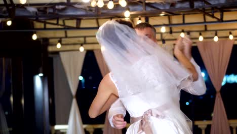 noche-de-invierno,-una-terraza-decorada-con-focos-de-luz,-en-la-calle,-los-novios-están-bailando-su-primer-baile-de-boda,-un-vals.-boda-de-invierno