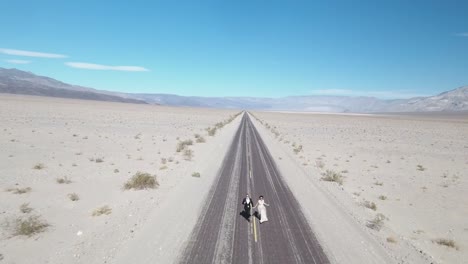 Braut-und-Bräutigam,-die-auf-leere-Wüstenstraße-im-Death-Valley,-USA