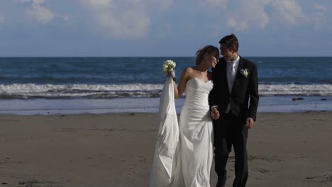 Feliz-pareja-de-recién-casados-caminando-por-la-playa