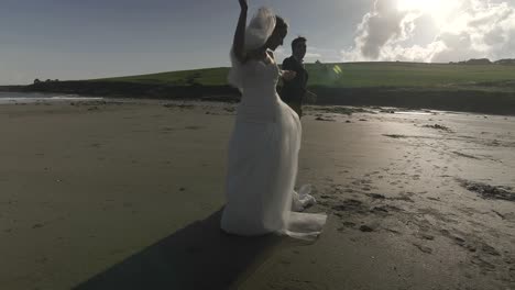 Sonriente-pareja-de-recién-casados-bailando-en-la-playa