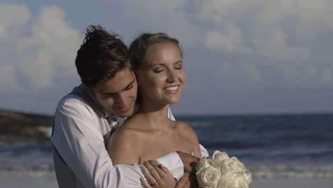 Sonriente-pareja-de-recién-casados-abrazar-en-la-playa