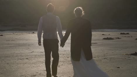 Sonriente-pareja-de-recién-casados-caminando-juntos-en-la-playa