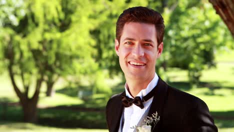 Attractive-groom-walking-towards-and-smiling-at-camera