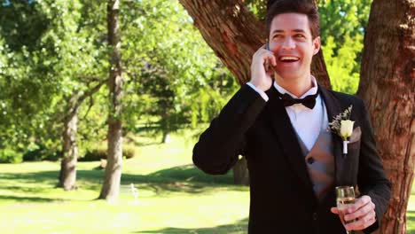 Happy-groom-drinking-champagne-and-chatting-on-phone