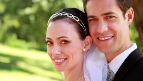 Attractive-newlyweds-smiling-at-camera-while-embracing