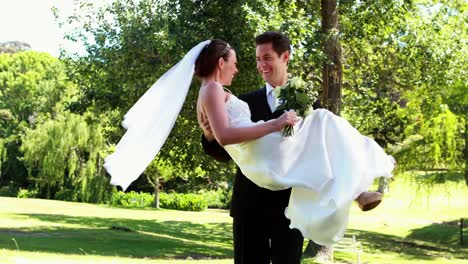 Groom-picking-up-his-pretty-new-wife-in-the-park