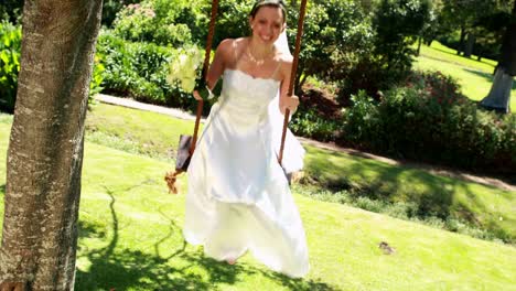 Smiling-bride-sitting-on-a-swing-looking-at-camera
