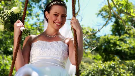 Happy-bride-sitting-on-a-swing-looking-at-camera