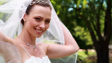 Pretty-bride-smiling-at-camera-and-lifting-her-veil
