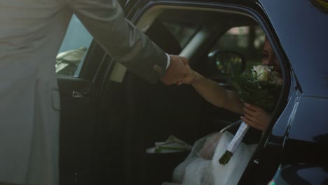 Groom-opens-and-holds-the-car-door-for-the-beautiful-young-bride.