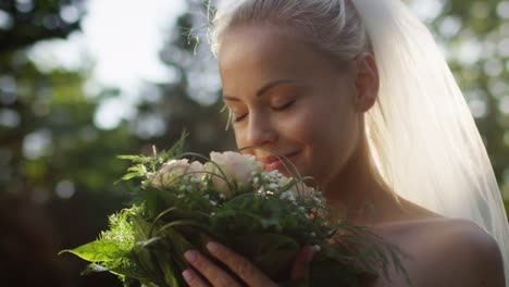 Portrait-of-a-bride-in-wedding-dress-with-flowers-in-a-sunny-park.