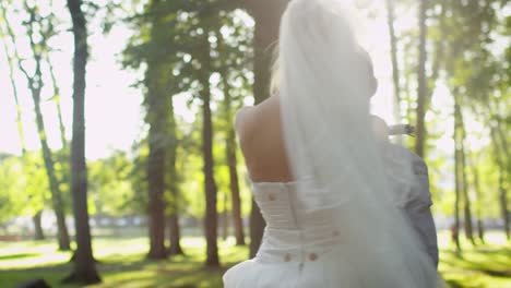 Bride-and-groom-hug-each-other-in-a-sunny-park.