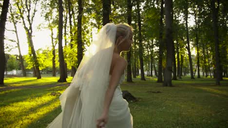 Bride-is-Asking-Groom-to-Join-her-in-the-Park.-Smiling-bride-who-is-running-in-the-park-is-asking-groom-to-join-and-give-her-his-hand.