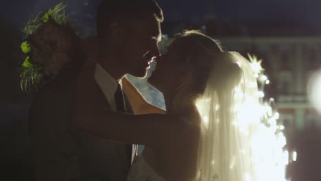 Felices-jóvenes-recién-casados-se-besan-al-lado-de-los-fuegos-artificiales-en-un-parque-en-la-noche.