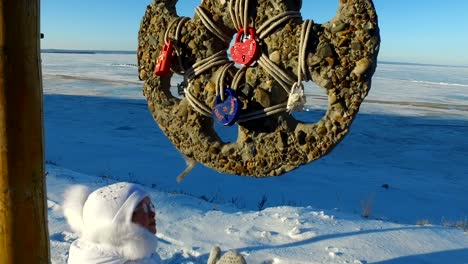 Girl-child-learns-wedding-amulet.-The-child-is-very-interesting,-what-it-is.-Winter-walk-in-the-park.-Frosty-winter-day.