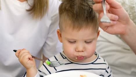 Kleine-entzückende-Junge-feiert-seinen-Geburtstag-mit-Vater-und-Mutter-essen-Kuchen-und-trinken-Tee