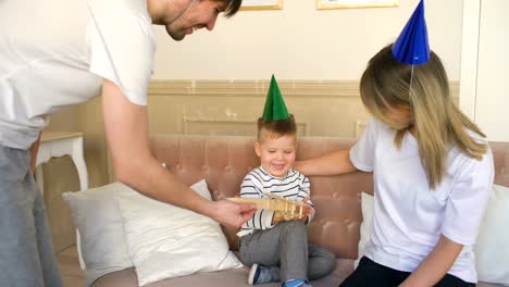 Vater-der-glückliche-Familie-anwesend-Geburtstagsgeschenk-zu-seinem-Sohn-zu-Hause-feiern