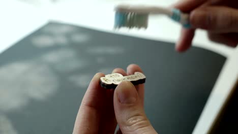 An-artist-cleans-with-brush-a-wooden-craft-after-grinding-on-sandpaper