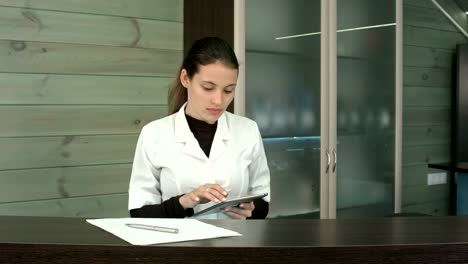 Woman-at-spa-reception-desk-uses-tablet-pc-texting-to-client