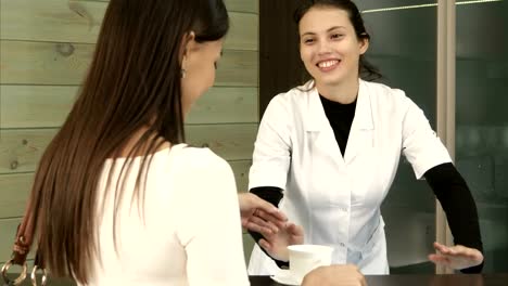 Smiling-spa-manager-serving-tea-to-female-customer-at-the-reception-desk