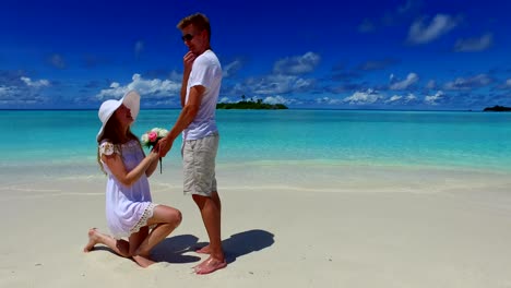 v07390-Maldives-white-sandy-beach-2-people-young-couple-man-woman-proposal-engagement-wedding-marriage-on-sunny-tropical-paradise-island-with-aqua-blue-sky-sea-water-ocean-4k