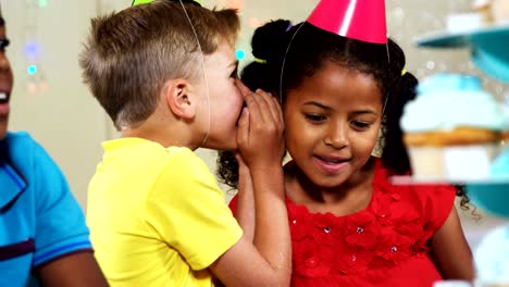 Niño-susurrando-a-chica-sentado-con-amigos-en-cumpleaños-partido-4k