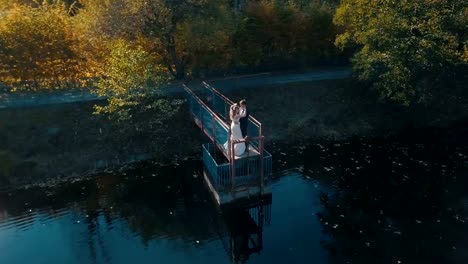 Pareja-joven-está-de-pie-sobre-un-pequeño-puente-cerca-del-lago-hermoso