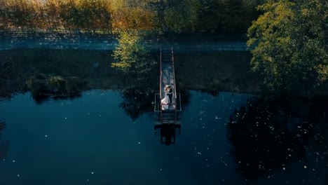 Pareja-joven-está-de-pie-sobre-un-pequeño-puente-cerca-del-lago-hermoso