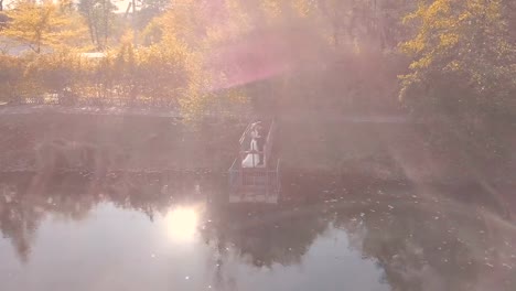 Young-wedding-couple-is-standing-on-a-small-bridge-near-beautiful-lake