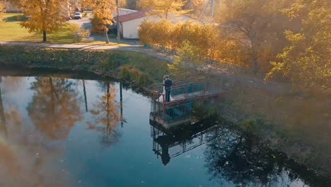 Pareja-joven-está-de-pie-sobre-un-pequeño-puente-cerca-del-lago-hermoso