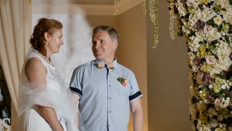 Happy-adult-couple-getting-married-under-flower-arch